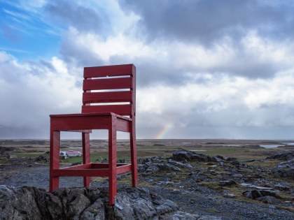 Большой красный деревяный стул на каменистой почве на подъездах к Eystrahorn — Восточному Рогу, Восточная Исландия. Фото Стасмир. Photo Stasmir.
